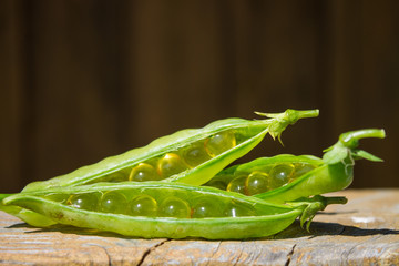 Green peas and omega-3 capsules on wooden background