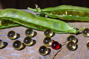 Green peas and omega-3 capsules on wooden background