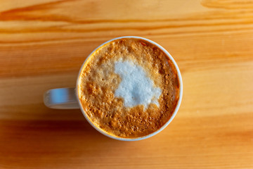 Mug of cappuccino on a wood table In natural light top view.