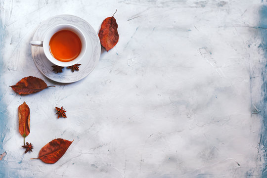 A cup of hot tea with fall leaves and copy space