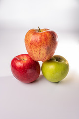 Red, green, and orange red delicious, granny smith, and fuji apples in a group isolated against a white background