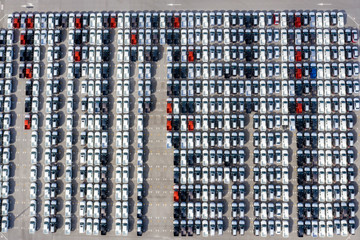 Aerial top view new cars lined up in the port for import export business logistic and transportation by ship in the open sea. New cars from the car factory parked at the port
