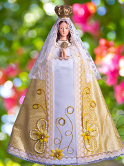 Imagen de la Virgen María, presentada como Virgen del Valle del Espíritu Santo, vestida en un rico traje blanco y dorado.