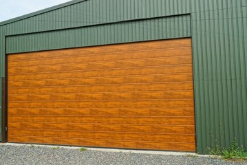 large brown gate on the green metal wall of a street garage
