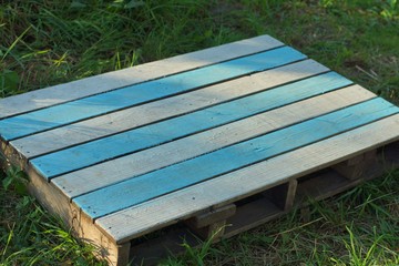 striped colored wooden table from the pallet lies on the green grass in the park