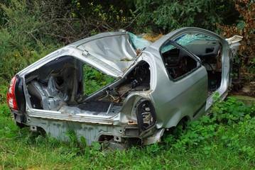 frame one gray disassembled car in the grass