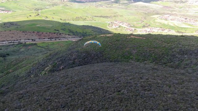 Para-glider over the top of the mountain during summer sunny day. Para-glider on the para-plane, strops -soaring flight moment flying over Black Mountain in San Diego, California. USA