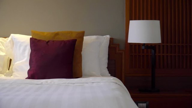 Pull back from Maroon and Gold decorative pillow along the edge of a hotel bed.
