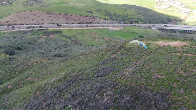 Para-glider over the top of the mountain during summer sunny day. Para-glider on the para-plane, strops -soaring flight moment flying over Black Mountain in San Diego, California. USA