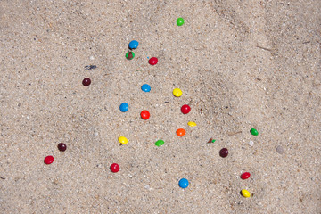 Close-up full frame view of chocolate candies dropped on the beach sand
