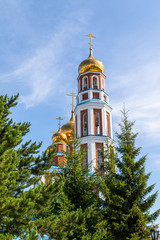 Fototapeta na wymiar Petropavlovsk, Kazakhstan - August 20, 2019: Orthodox church with golden domes against the sky. Nature, green trees, landscape.