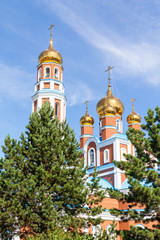 Fototapeta na wymiar Petropavlovsk, Kazakhstan - August 20, 2019: Orthodox church with golden domes against the sky. Nature, green trees, landscape.