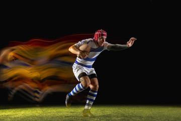 New star of the competitive. One caucasian man playing rugby on the stadium in mixed light. Fit young male player in motion or action during sport game. Concept of movement, sport, healthy lifestyle.