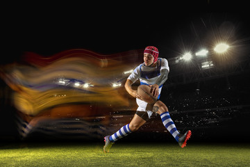 New star of the competitive. One caucasian man playing rugby on the stadium in mixed light. Fit young male player in motion or action during sport game. Concept of movement, sport, healthy lifestyle.