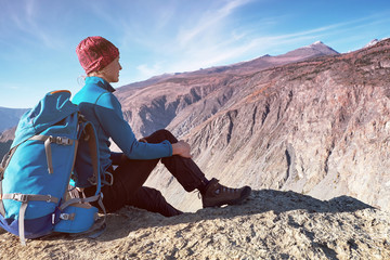 Fototapeta premium Hiker woman with backpack sitting on rock of a mountain