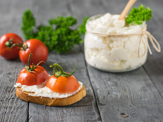 Cherry tomatoes with cottage cheese and toasted bread on a wooden table.