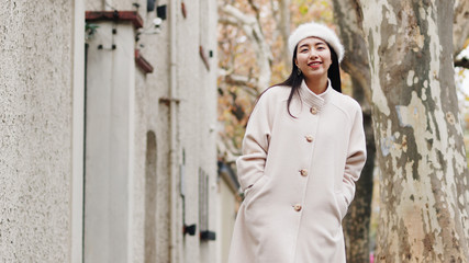 Beautiful young brunette woman in white beret and woolen sweater posing with blur street background. Outdoor fashion portrait of glamour young Chinese cheerful stylish lady, street photography.