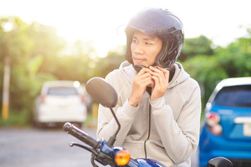 Before riding a motorcycle, a handsome Asian man wore a helmet. road safety