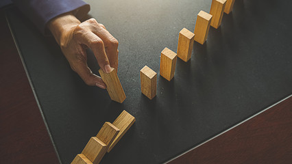 Problem Solving,Close up view on hand of business woman stopping falling blocks on table for concept about taking responsibility.