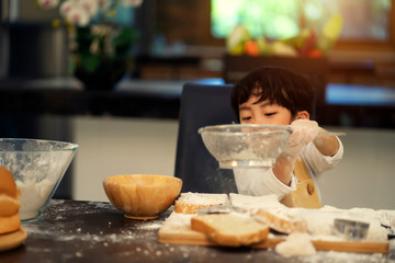 Kid boy enjoying preparing ingredients for making cakes.Boys learn to make cakes in the kitchen.The boy is cooking in the kitchen.