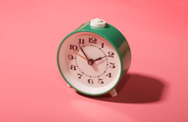 vintage green mechanical alarm clock isolated on pink background