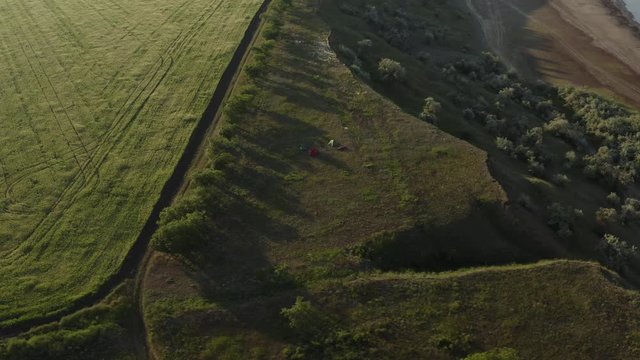 Aerial top view of small tent camp on lake shore at sunset drone footage