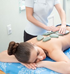 Obraz na płótnie Canvas Pretty girl getting hot stone massage in spa salon