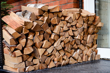 Stacked firewood. A brick wall in the background.