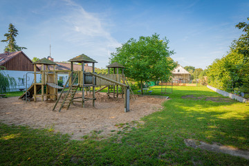a wooden climbing frame stands on the premises of a kindergarten