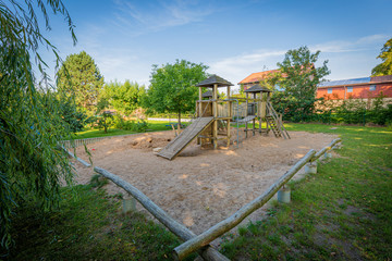 a wooden climbing frame stands on the premises of a kindergarten