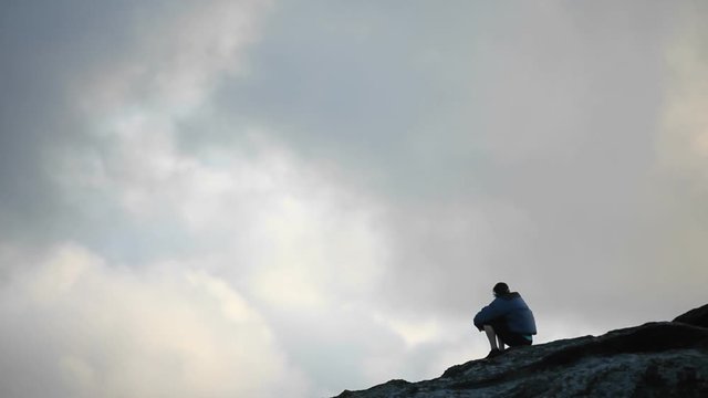 A man sits atop of an elevated area and takes in the view.