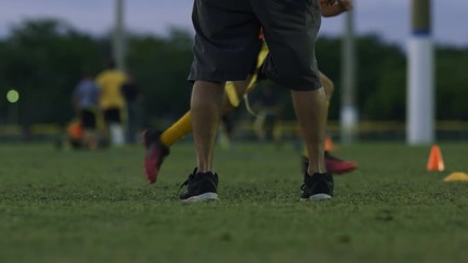 Cool slow motion of kids running by coach during flag football practice