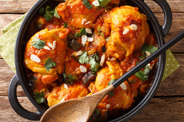 African cuisine chicken stew with eggplant, almonds in tomato sauce close-up in a pan. Horizontal top view
