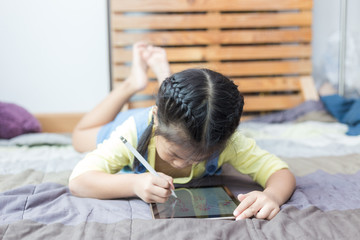 Asian school child girl drawing on tblet computer by hand