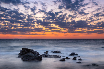 Fototapeta na wymiar Long exposure Sunset Sea Rocks Clouds