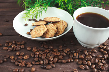 Cup of coffee, coffee beans and cookies on a dark wooden table