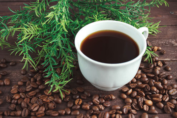 Cup of coffee, coffee beans on a dark wooden table