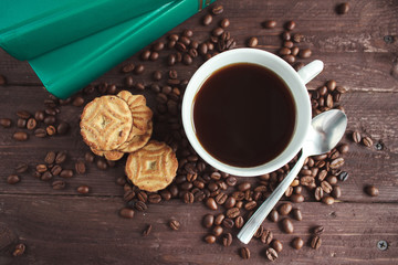 Cup of coffee, coffee beans and cookies on a dark wooden table