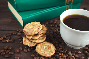 Cup of coffee, coffee beans and cookies on a dark wooden table