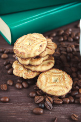 Coffee beans, cookies and book on a dark wooden table