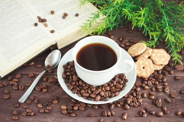 Cup of coffee, coffee beans and cookies on a dark wooden table