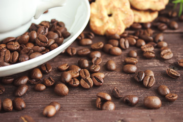 Cup of coffee, coffee beans and cookies on a dark wooden table