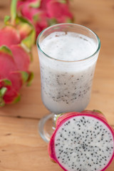 Dragon fruit smoothie on wooden table.