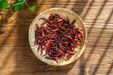 The sun shines on a bamboo sieve on a wooden table.