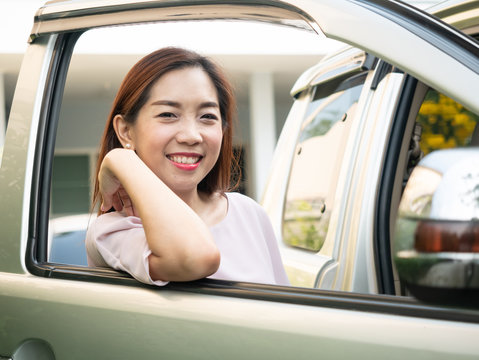 Asian woman standing beside a car.