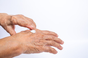 Fototapeta premium Senior Woman applying moisturising cream on her hands isolated on white background, Asian beauty skin concept
