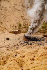 Grey smoke comes out from smoke bomb. The bomb on sand near a forest. Military training. Air...