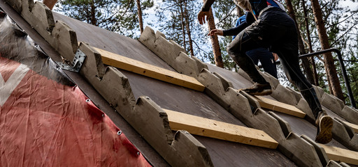 A man climbs an obstacle at a sporting event. He hard goes up on top of obstacle. Sport activity in the forest