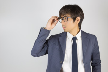 Fototapeta na wymiar Young Asian Portrait Businessman in Navy Blue Suit Touch Eyeglasses and Look Beside