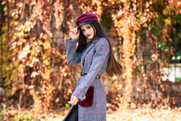 Fototapeta na wymiar Young beautiful girl wearing winter coat and cap in autumn leaves background.